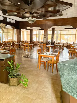 a dining room with wooden tables and chairs at Aqaba Gulf Hotel By FHM in Aqaba