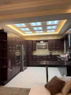 a kitchen with wooden cabinets and a ceiling with lights at Modern Luxe Getaway in Amman