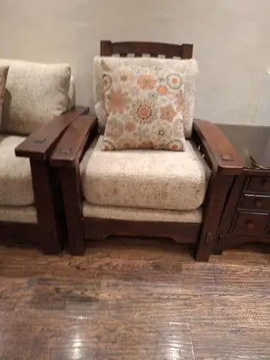 a couch with a pillow and a wooden table at شقه مفروشه in Jurf ad Darāwīsh