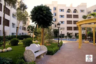 a park with white benches in front of a building at Der Ghbar Luxe in Amman
