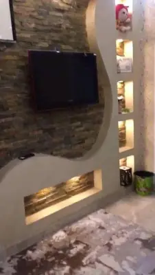 a flat screen tv on a stone wall with a fireplace at الازرق فارم in Al Azraq ash Shamālī