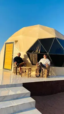two men sitting in chairs in a tent at Wadi Rum Sha ar Nights in Wadi Rum