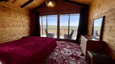 a bedroom with a bed and a large window at كوخ واستراحة شيخ الجبل in Ajloun