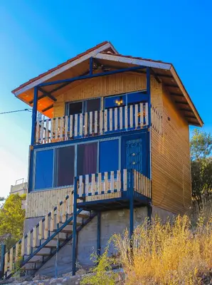 a house with a balcony on the side of it at كوخ واستراحة شيخ الجبل in Ajloun