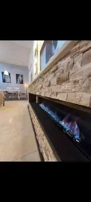 a fireplace in a living room with a stone wall at Central Jabal Alweibdeh in Amman