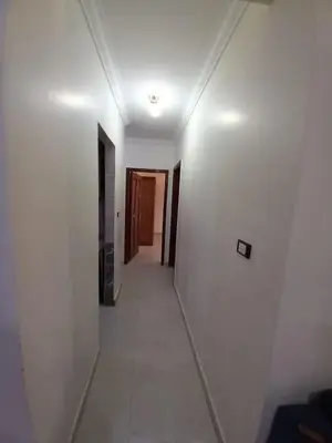 a long hallway with white walls and a hallway with doors at المزار لوج in Al Mazār