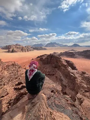 a person sitting on a rock in the desert at Wadi Rum Cave Experience in Wadi Rum
