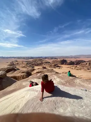 a group of people sitting on top of a desert at Wadi Rum Cave Experience in Wadi Rum