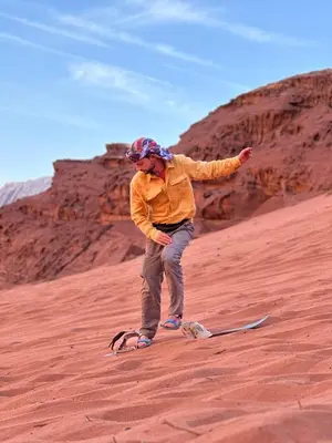 a man standing on a snowboard in the desert at Wadi Rum Cave Experience in Wadi Rum