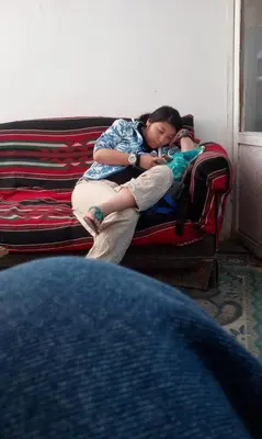 a woman sitting on a couch holding a child at man -soor in Amman
