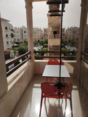 two chairs and a table on a balcony with a view at Khalda One Bedroom Apt in Amman
