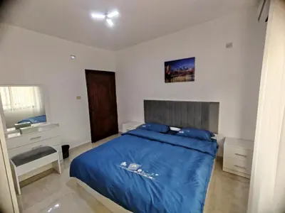a bedroom with a blue bed and a sink at Khalda One Bedroom Apt in Amman