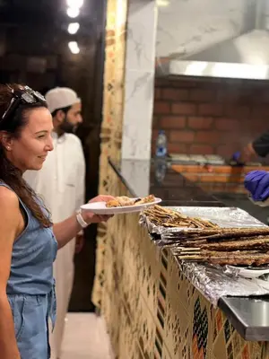 a woman is holding a plate of food at Wadi rum camp hamod in Wadi Rum