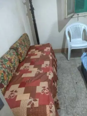 a bed with a quilt and a chair in a room at هيوم شليت in Um Qeis