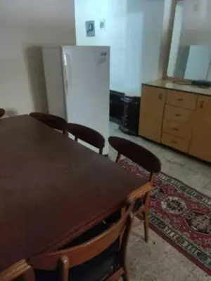 a kitchen with a table and chairs and a refrigerator at هيوم شليت in Um Qeis
