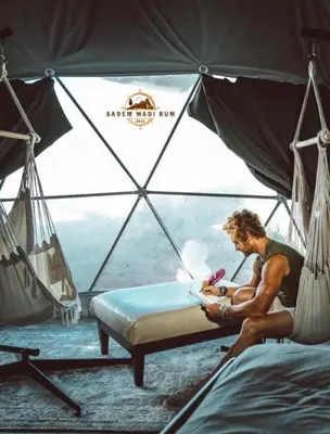 a man sitting on a bed in a tent at SADEM WADl RUM in Wadi Rum