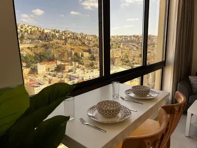 a white table with two cups and plates on it at Central Amman Stunning Views Apt in Amman