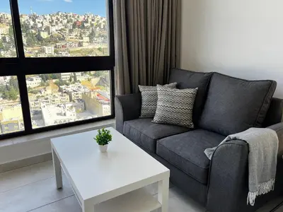 a living room with a couch and a table at Central Amman Stunning Views Apt in Amman