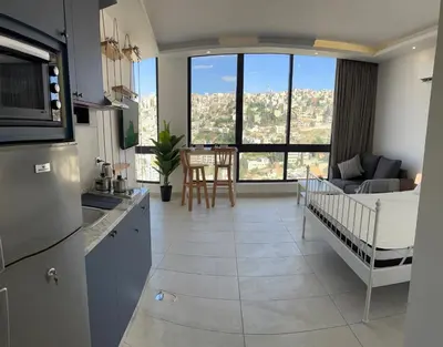 a kitchen and living room with a baby crib in it at Central Amman Stunning Views Apt in Amman