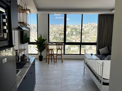 a kitchen and living room with a view of a city at Central Amman Stunning Views Apt in Amman