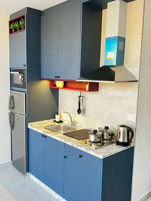a small kitchen with blue cabinets and a sink at Modern Studio Apartment Near Downtown, breathtaking view! in Amman