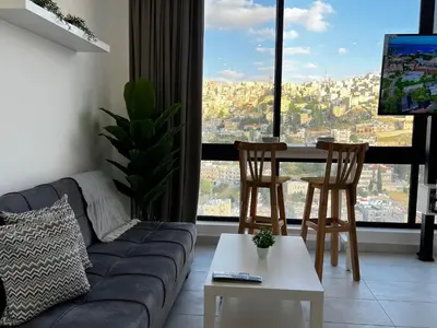 a living room with a couch and a table and chairs at Modern Studio Apartment Near Downtown, breathtaking view! in Amman
