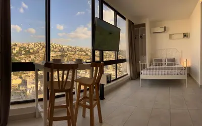 a room with a bed and a table and chairs at Modern Studio Apartment Near Downtown, breathtaking view! in Amman