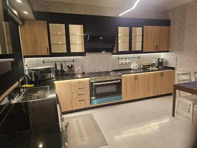 a kitchen with wooden cabinets and a stove top oven at شقة 3غرف نوم في ضاحية الرشيد in Amman