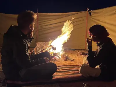 two people sitting around a fire in a tent at Wadi Rum Starlit in Wadi Rum