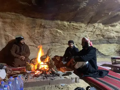 a group of people sitting around a campfire at Wadi Rum Starlit in Wadi Rum