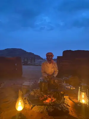 a man sitting in front of a camp fire at Wadi Rum Starlit in Wadi Rum