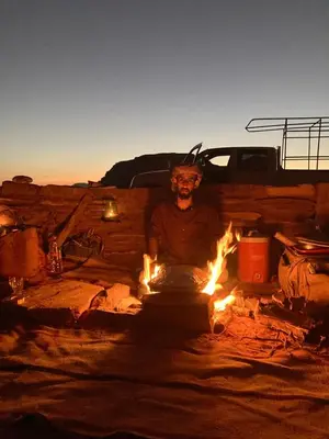 a man sitting in front of a fire at Wadi Rum Starlit in Wadi Rum