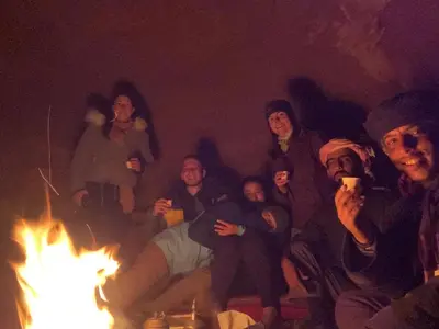 a group of people sitting around a fire at Wadi Rum Starlit in Wadi Rum