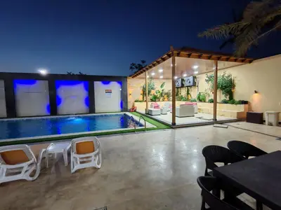 a swimming pool in a house with chairs around it at Wonder Villa in Al Rama