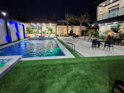 a swimming pool at night with tables and chairs at Wonder Villa in Al Rama