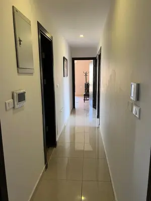 a hallway with white walls and tile floors and a mirror at Abdoun is comfortable accommodation and an exceptional location close to the mall in Amman