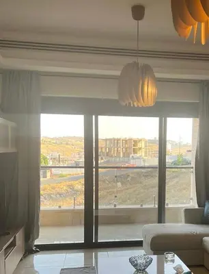a living room with a large window with a view at Abdoun is comfortable accommodation and an exceptional location close to the mall in Amman