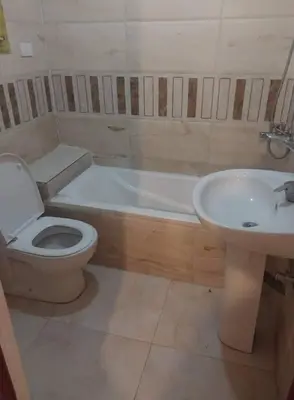 a bathroom with a toilet and a tub and a sink at ranos villa in An Nu‘ayyimah
