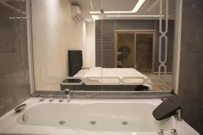 a bathroom with a bath tub and a bed in a mirror at Lumen villa in Umm Uthainah