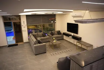 a living room with a couch and a tv at Lumen villa in Umm Uthainah