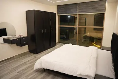 a bedroom with a large white bed and a large window at Lumen villa in Umm Uthainah