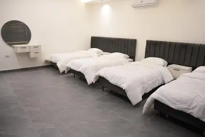 four beds lined up in a row in a room at Lumen villa in Umm Uthainah