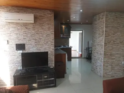 a living room with a tv and a brick wall at الاردن عمان تلاع العلي شارع ابو يوسف الأنصاري اسكان طارق الشيخ in Amman