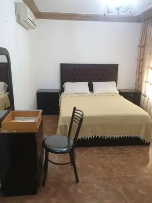 a bedroom with a bed with a chair and a table at الاردن عمان تلاع العلي شارع ابو يوسف الأنصاري اسكان طارق الشيخ in Amman