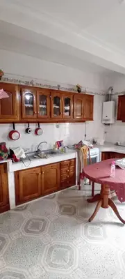 a kitchen with wooden cabinets and a table in it at النعيمه هاوس in An Nu‘ayyimah