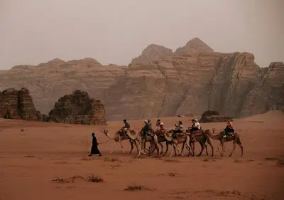 a group of people riding on camels in the desert at Rum Sky Experiences in Wadi Rum