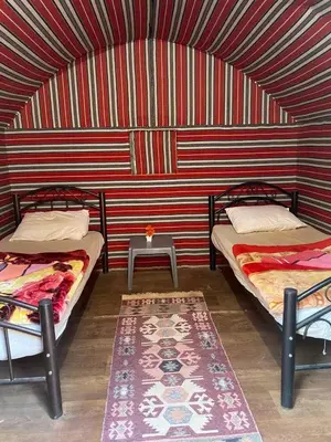two beds in a room with a red and white striped wall at Rum Sky Experiences in Wadi Rum