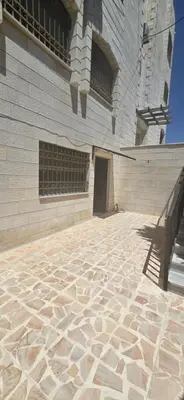 a building with a stone floor next to a building at الريان غرفتين نوم in Amman