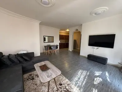 a living room with a black couch and a flat screen tv at Warm 1BR in Dabouq in Amman