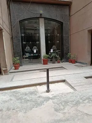 a bench in front of a building with potted plants at ام النعمان شليت in Umm as Surab